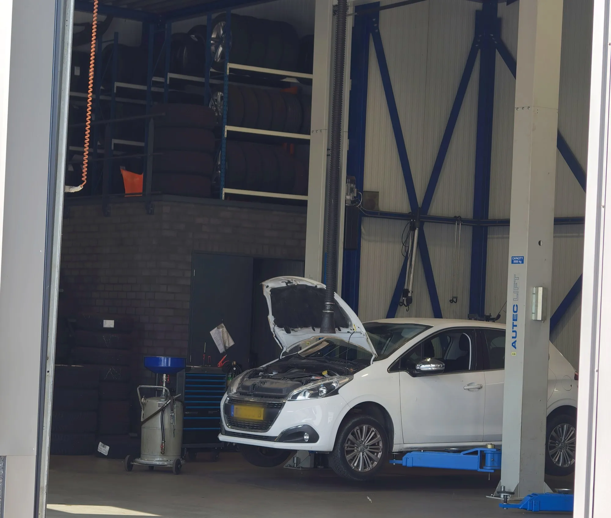 De werkplaats van Car Service Urk, met een auto op de hefbrug en de motorkap open.
